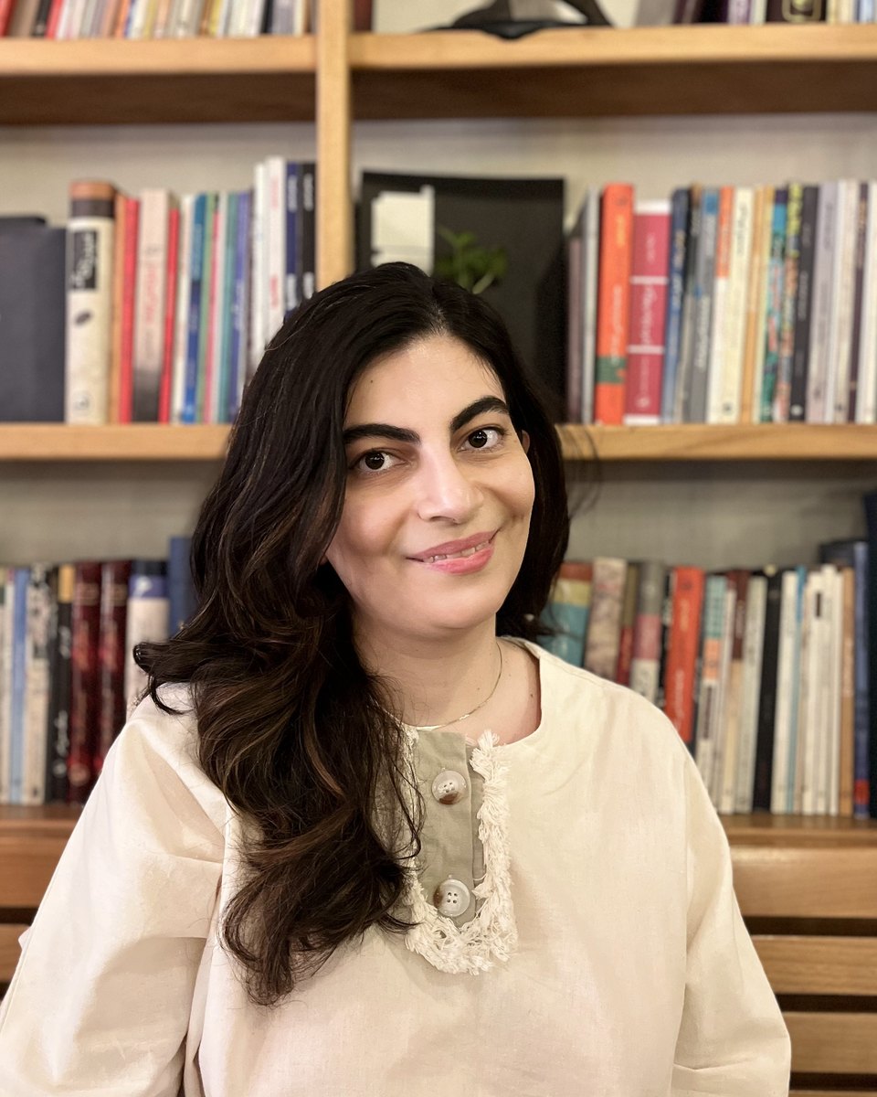 Mojgan Haratian, smiling, in front of a bookshelf